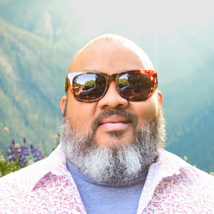 Confident man facing forward wearing Robust big head sunglasses with mountain background