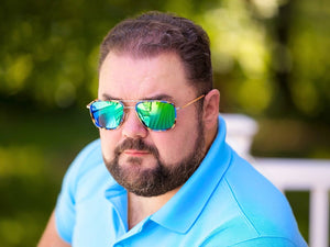 Man wearing reflective sunglasses and a blue shirt outdoors